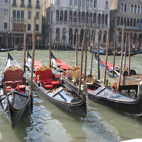 A small boat in a body of water with a city in the background - Gondola