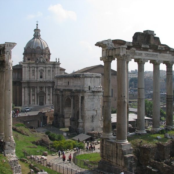 A statue of a stone building with Roman Forum in the background - Roman Forum